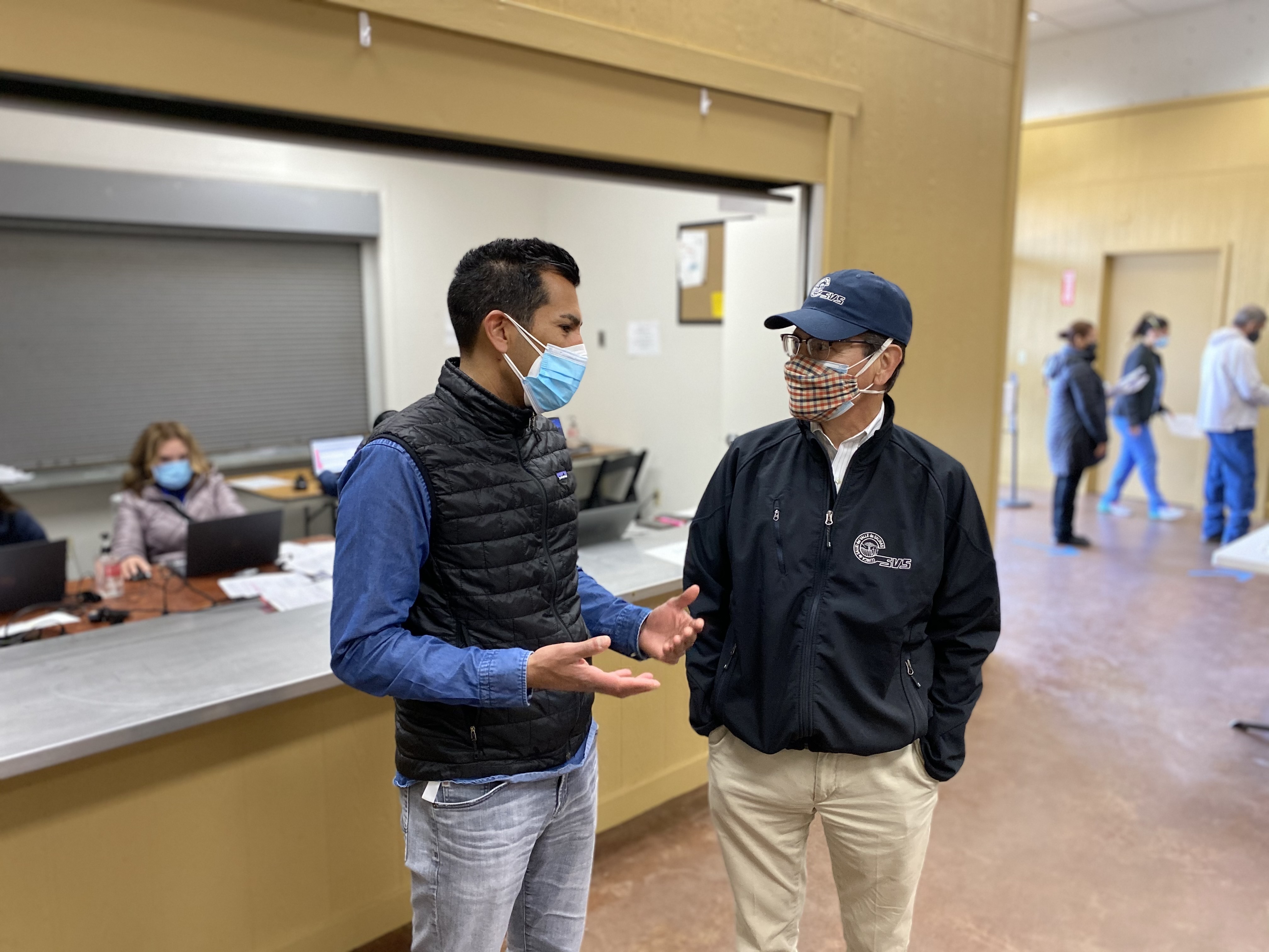(2020) Asm. Robert Rivas in a mask standing next to another individual in a mask in a medical setting. 